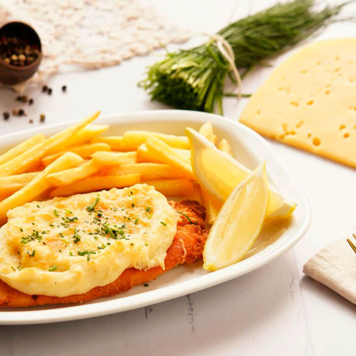 Plato de Milanesas de pollo a la suiza con papas rústicas y huevo a la plancha encima